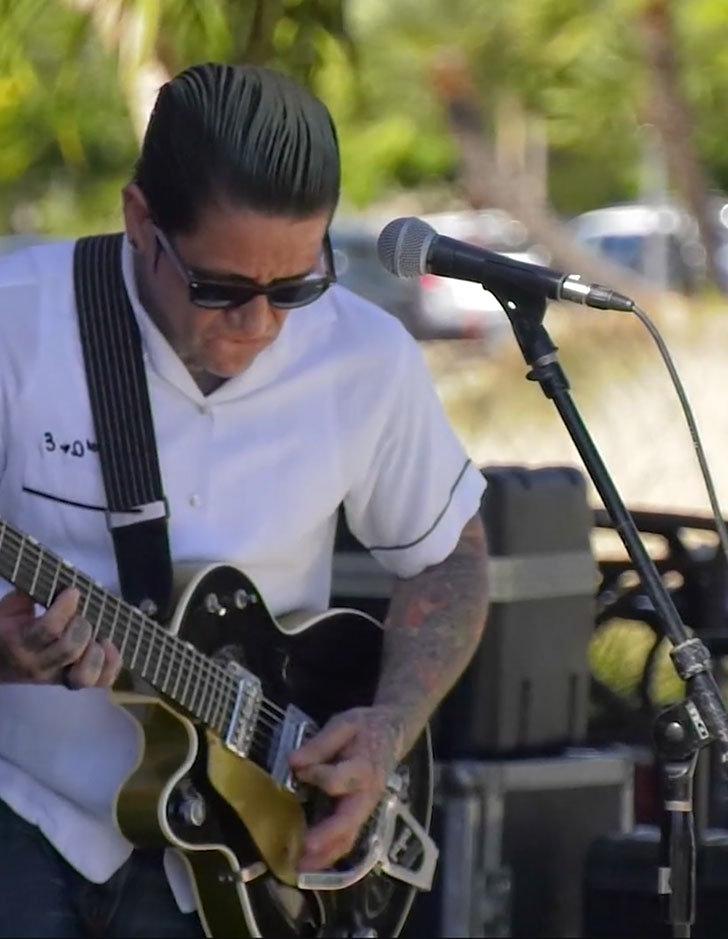 A band member plays an electric guitar onstage.